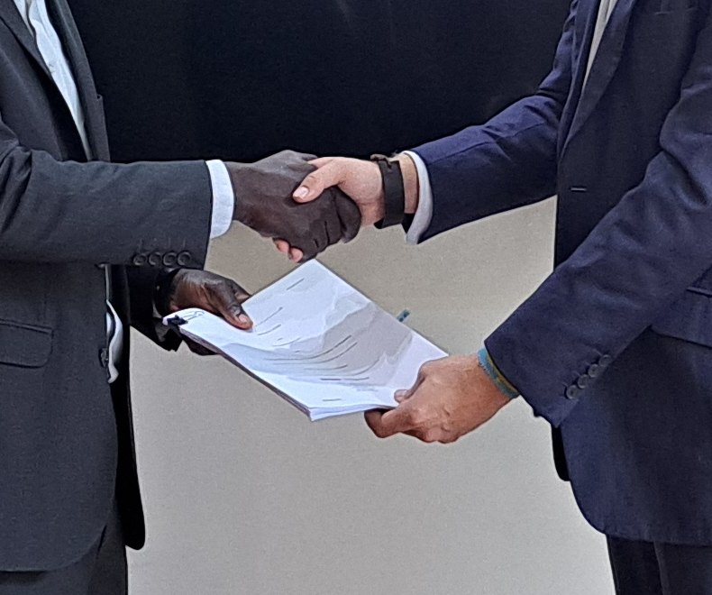 Two partners shaking hands over a signed agreement, sealing a deal